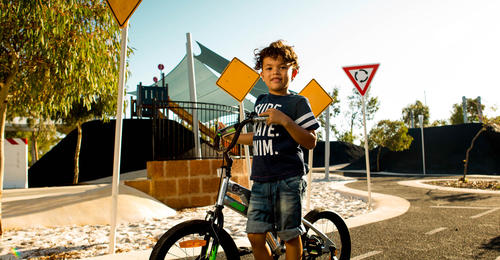 A child riding a bicycle in a kids cycling park at Banksia Grove