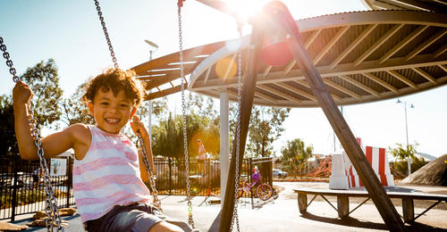A child swinging on a swing in a park at Banksia Grove